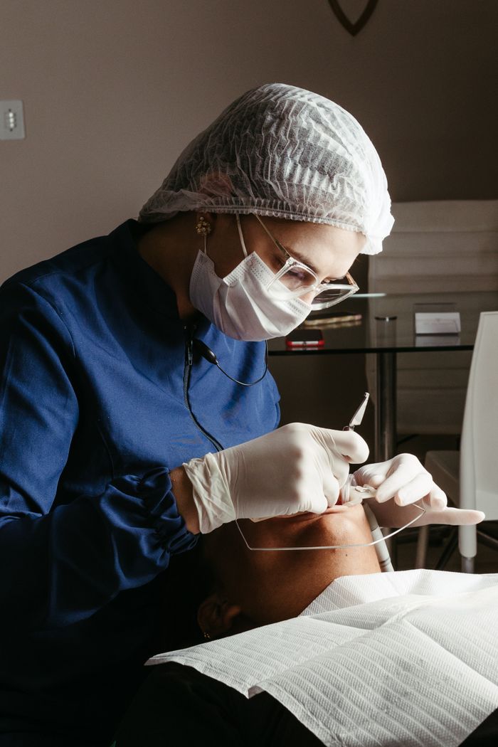 Mastering the First Impression: Your intriguing post title goes here A dentist in a medical clinic performing a procedure on a patient, focusing on dental care and hygiene.