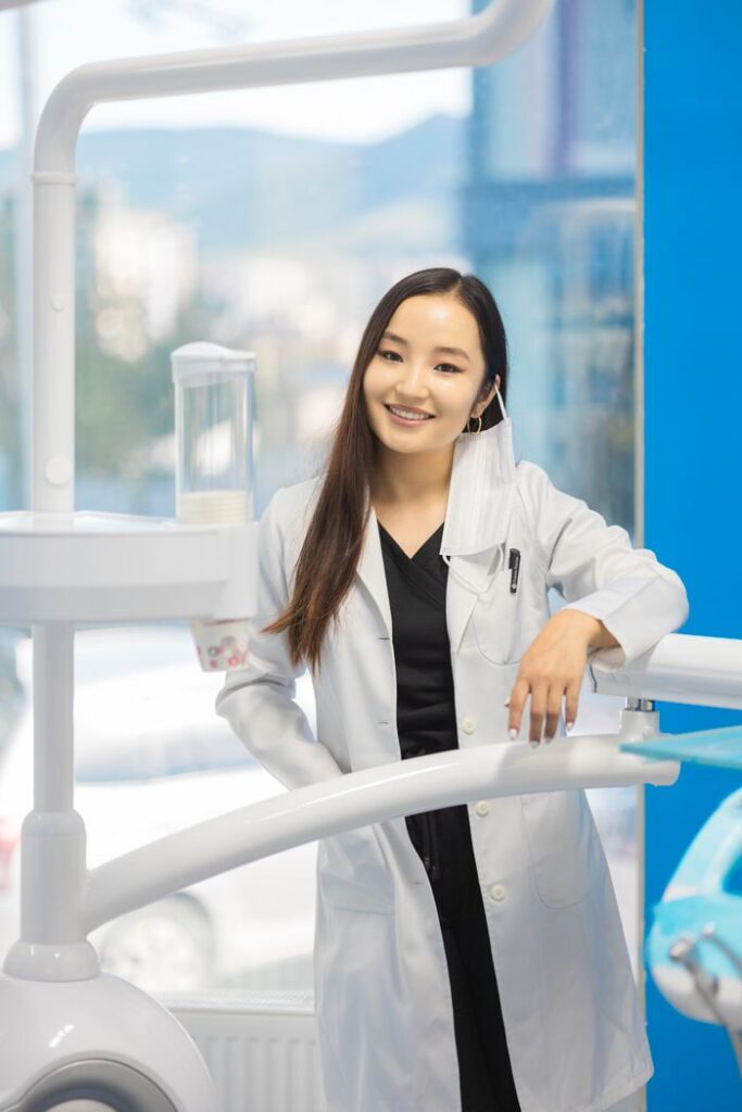 Asian dentist smiling confidently in a modern dental clinic with equipment.