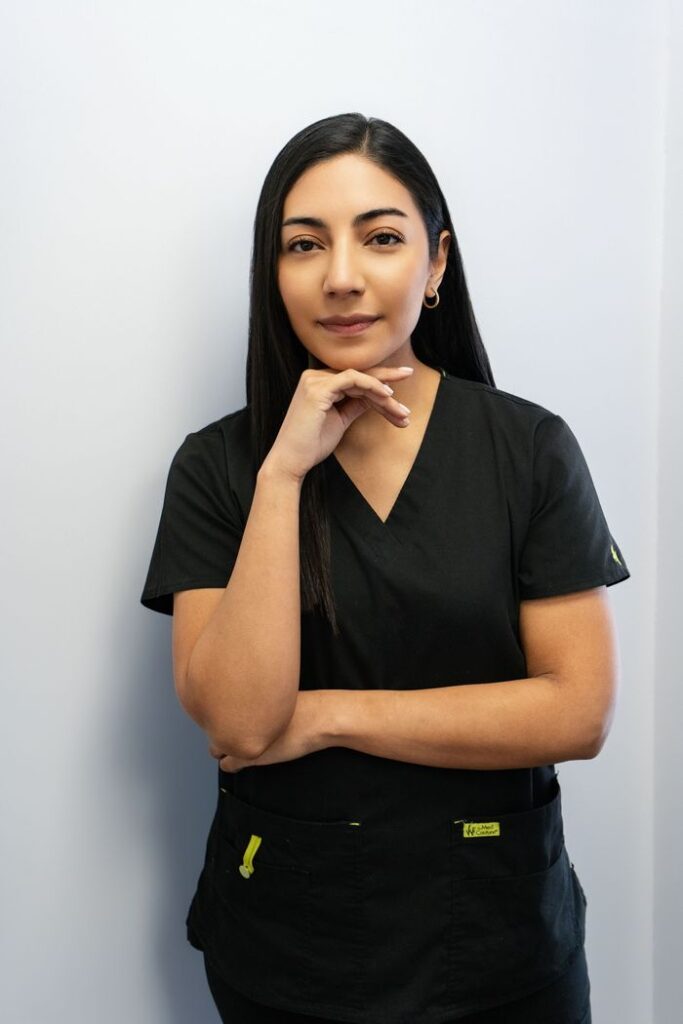 Portrait of a confident female dentist in black scrubs, standing indoors.